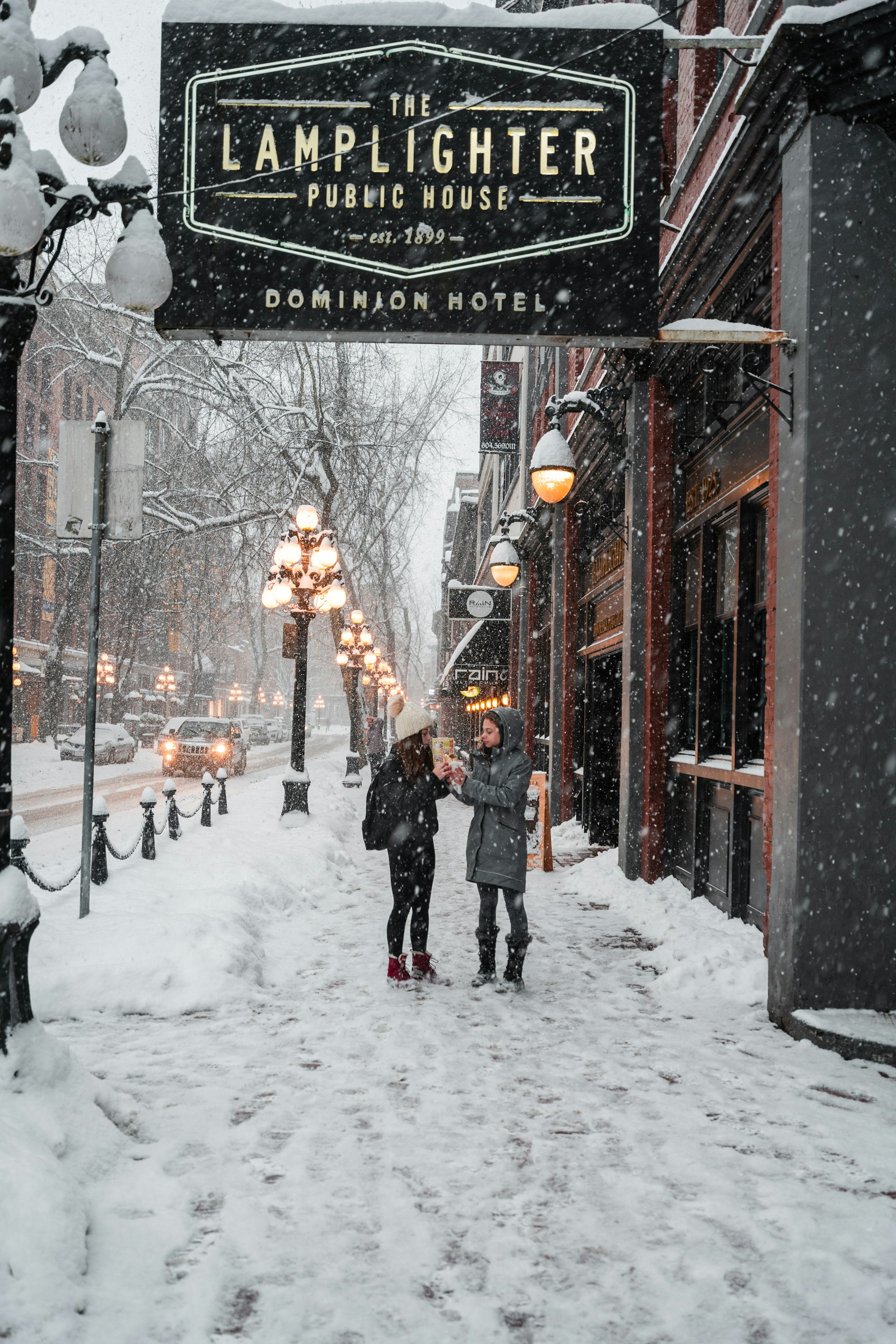 a couple of people walking down a snow covered street