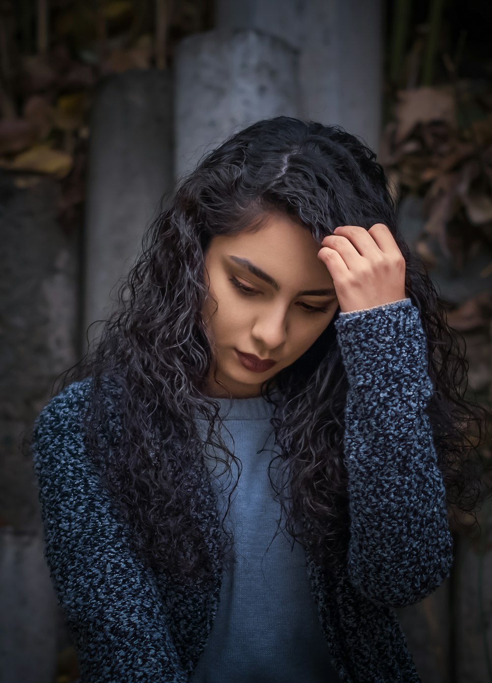 a woman with long curly hair holding her head