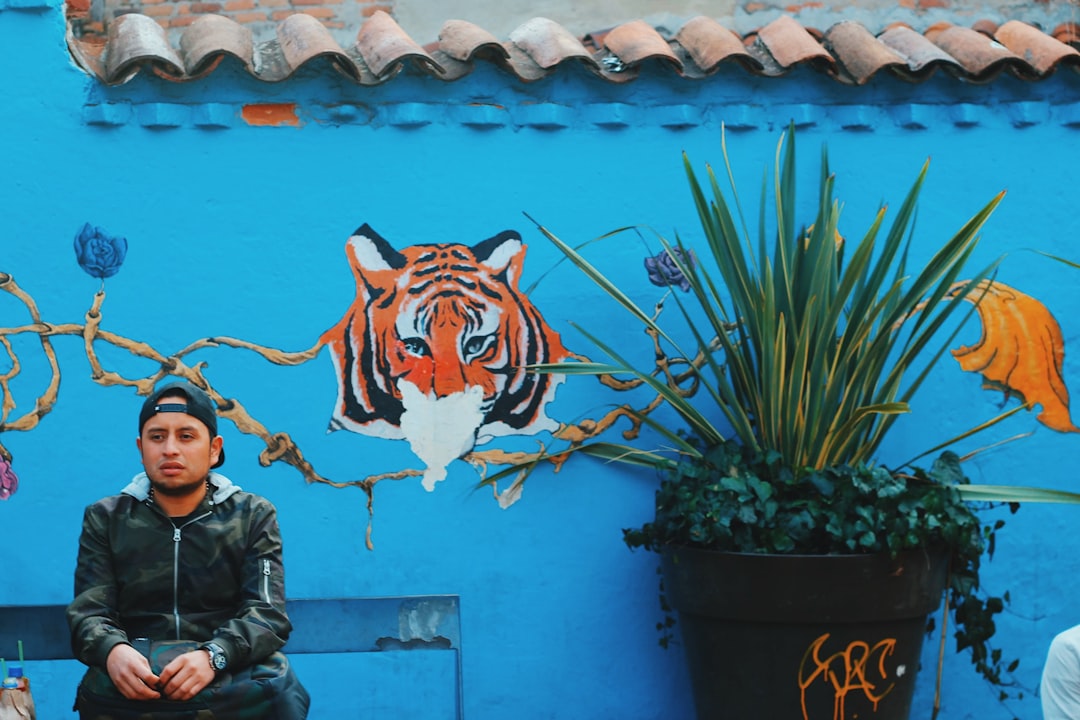 man in black leather jacket standing beside tiger wall art