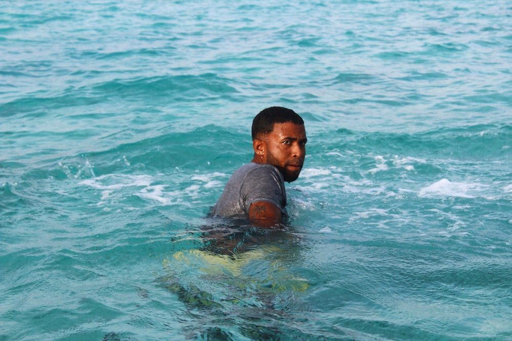 man in black shirt swimming in water during daytime