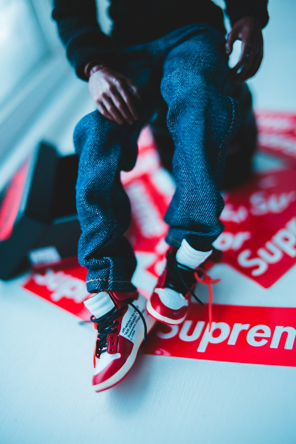 a person sitting on top of a supreme sticker