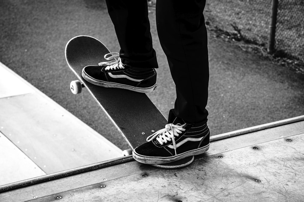 person in black pants wearing black and white sneakers