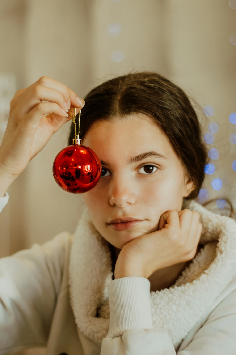 a woman holding a red ornament in front of her face
