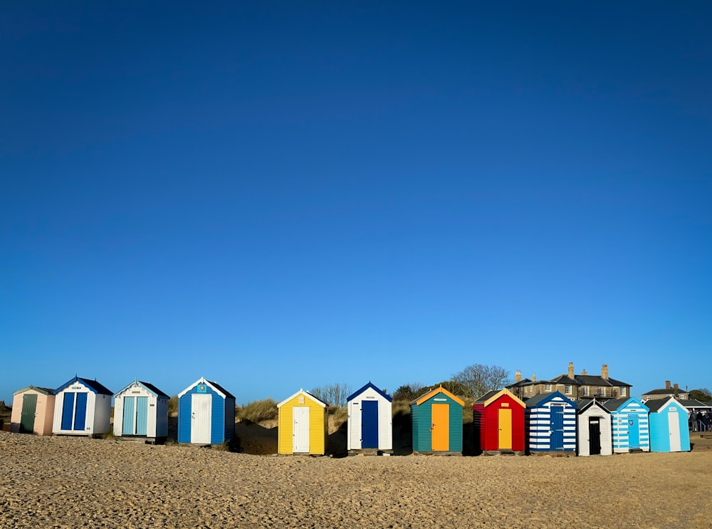 a row of colorful beach huts sitting on top of a sandy beach