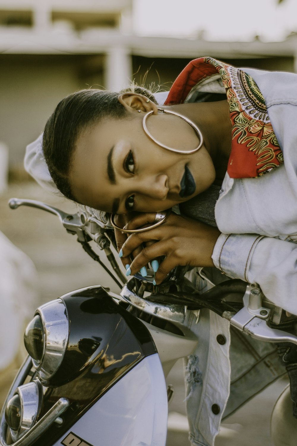 a woman leaning on the handle bars of a motorcycle