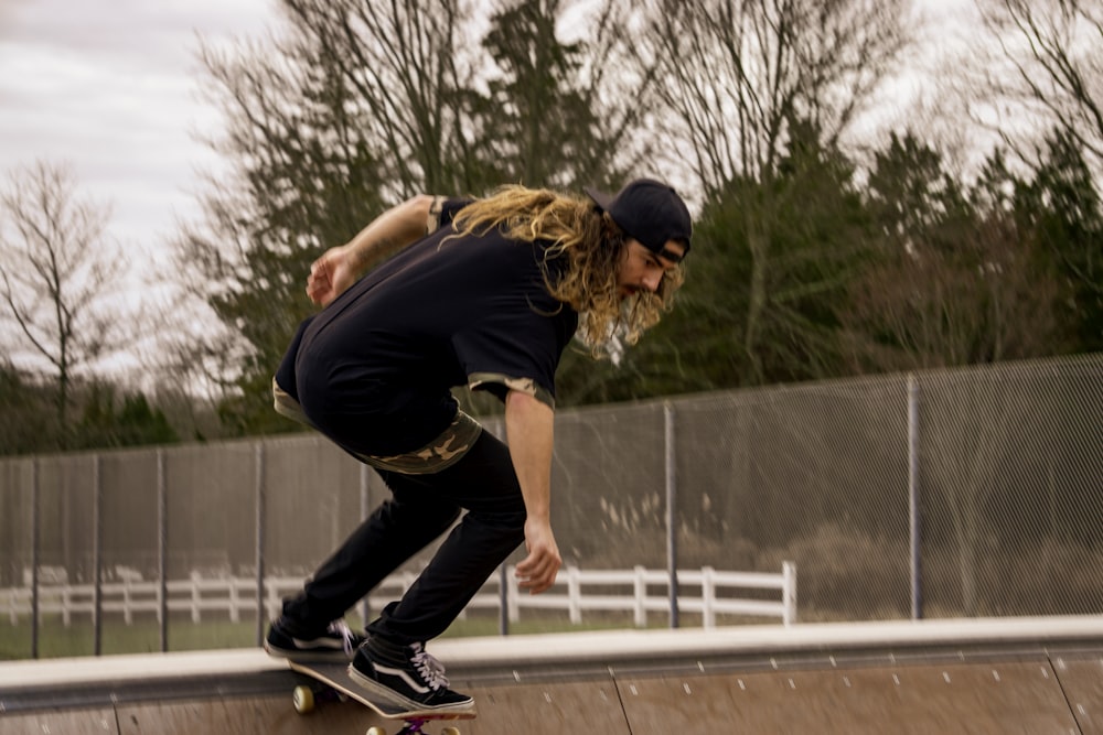 man in black t-shirt and black pants doing skateboard stunts during daytime