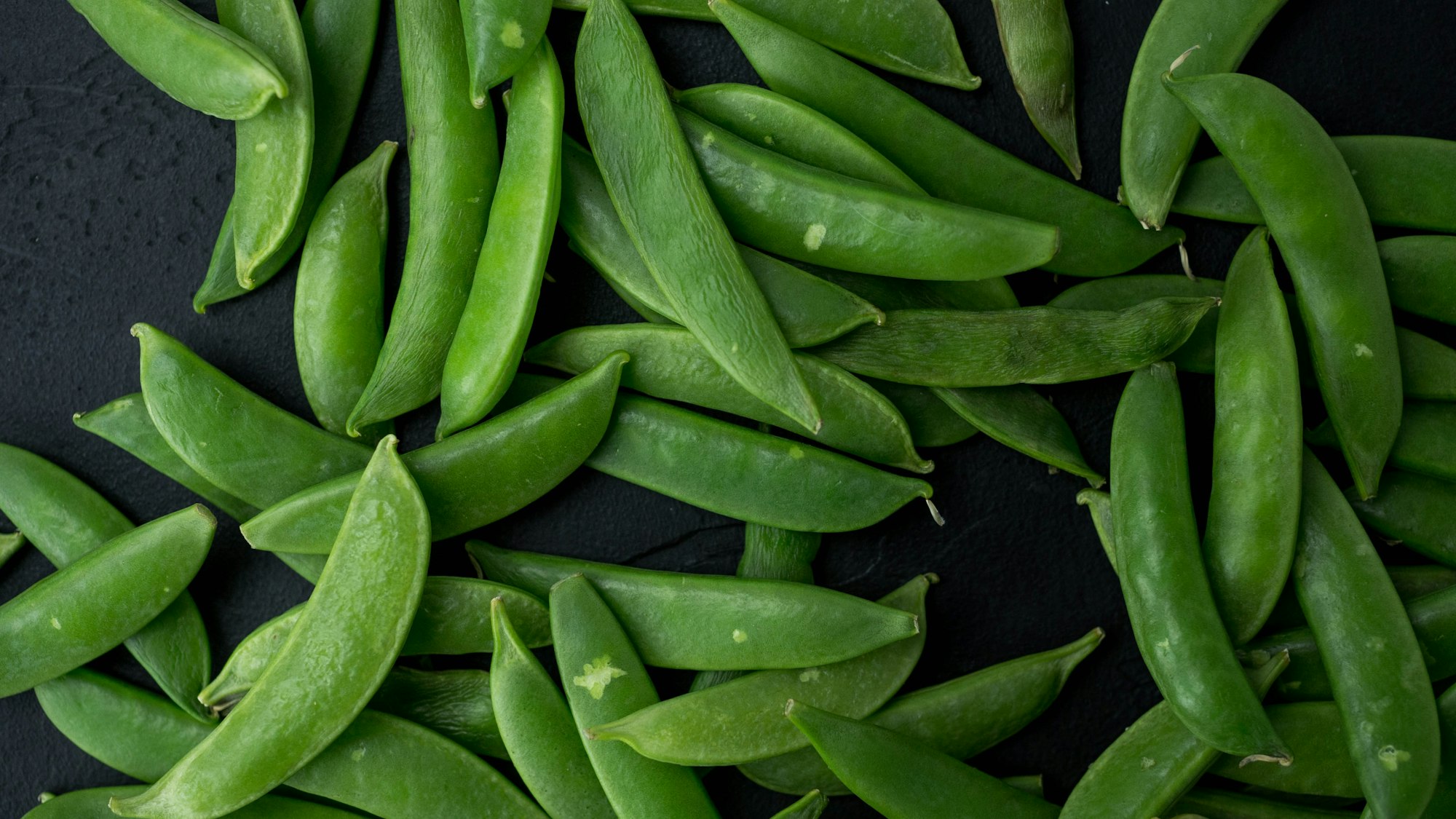 Green beans lying on a dark background close-up shot