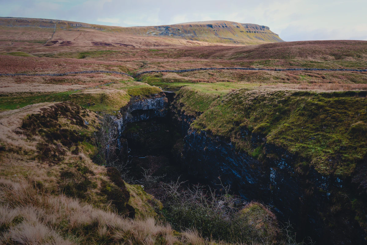 Hull Pot, a collapsed cave below Pen-y-ghent in the Yorkshire Dales, with a flat-topped fell behind