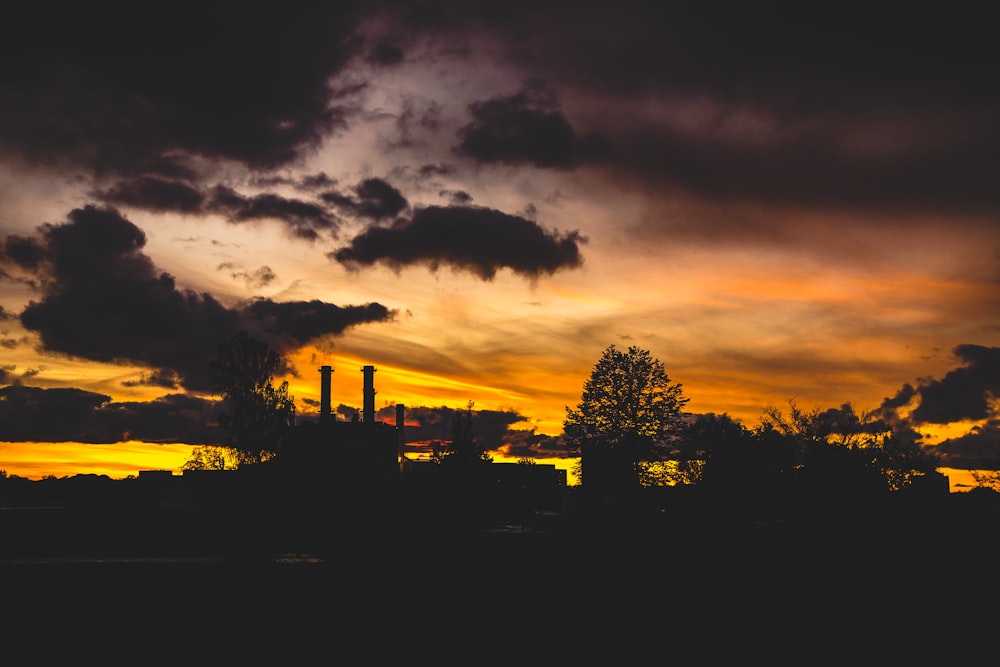 a sunset with smoke stacks in the distance