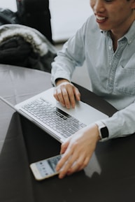 a man sitting at a table using a laptop computer