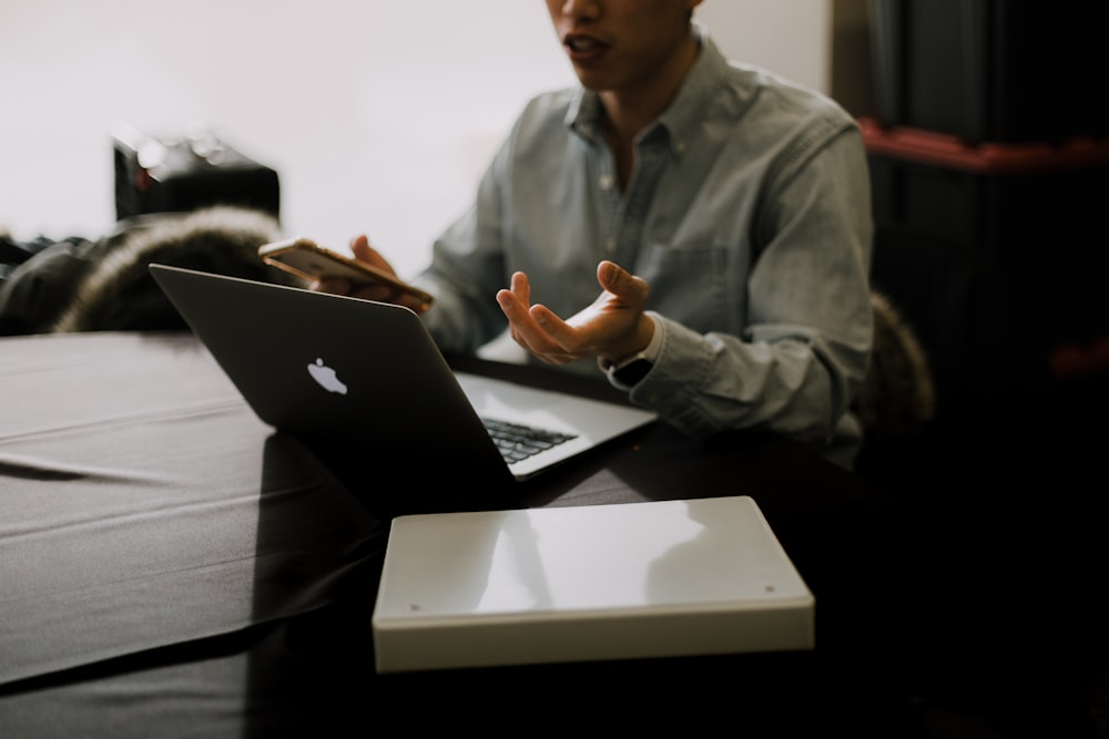 a man sitting at a table with a laptop in front of him