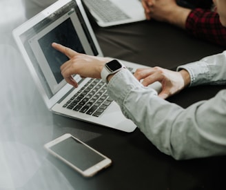 two people sitting at a table with laptops