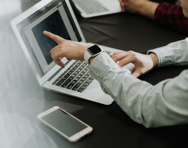 two people sitting at a table with laptops