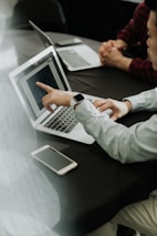 two people sitting at a table with laptops