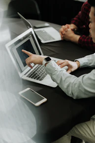 two people sitting at a table with laptops