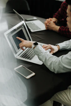 two people sitting at a table with laptops