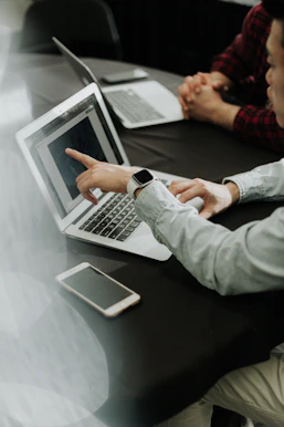two people sitting at a table with laptops