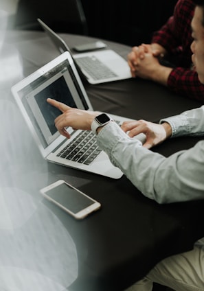 two people sitting at a table with laptops