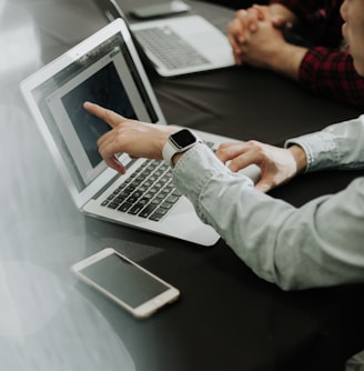 two people sitting at a table with laptops