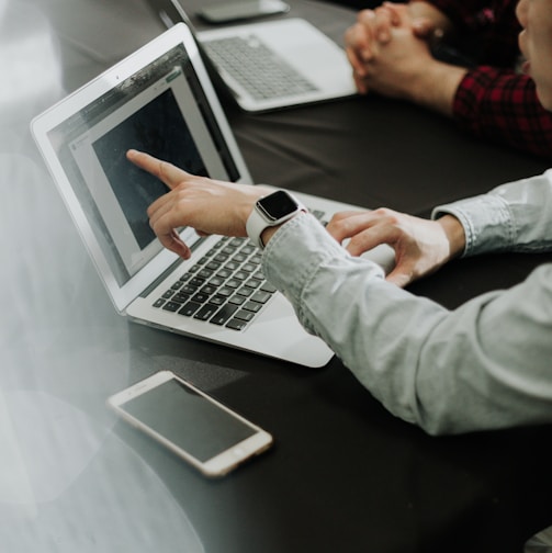 two people sitting at a table with laptops