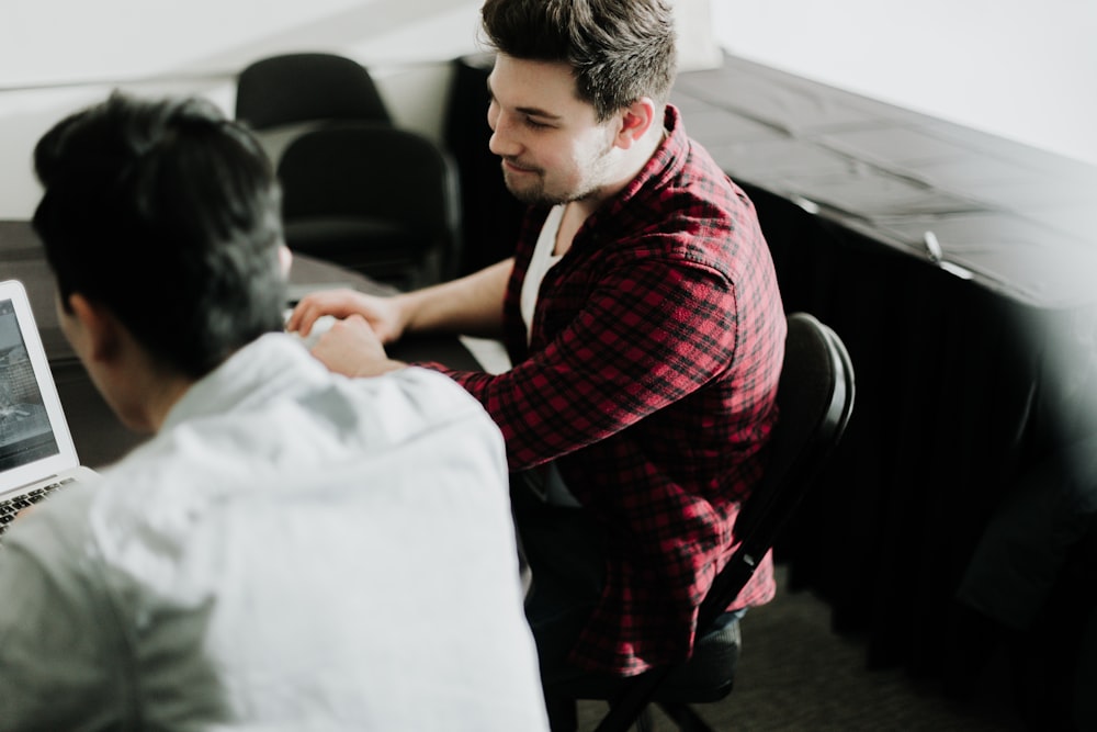 a man sitting at a desk shaking hands with another man