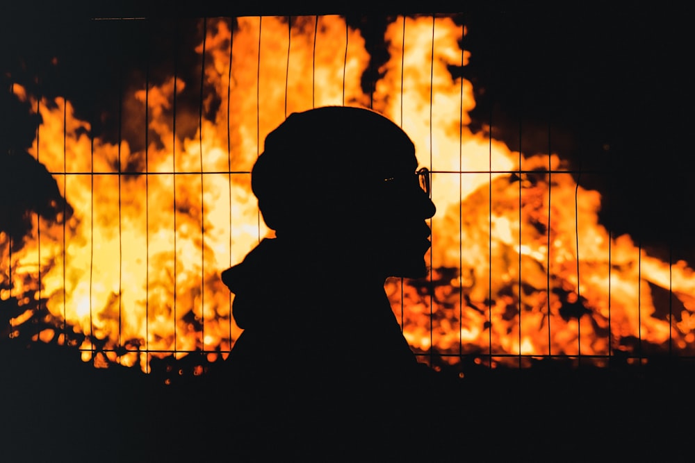 a silhouette of a man standing in front of a fire