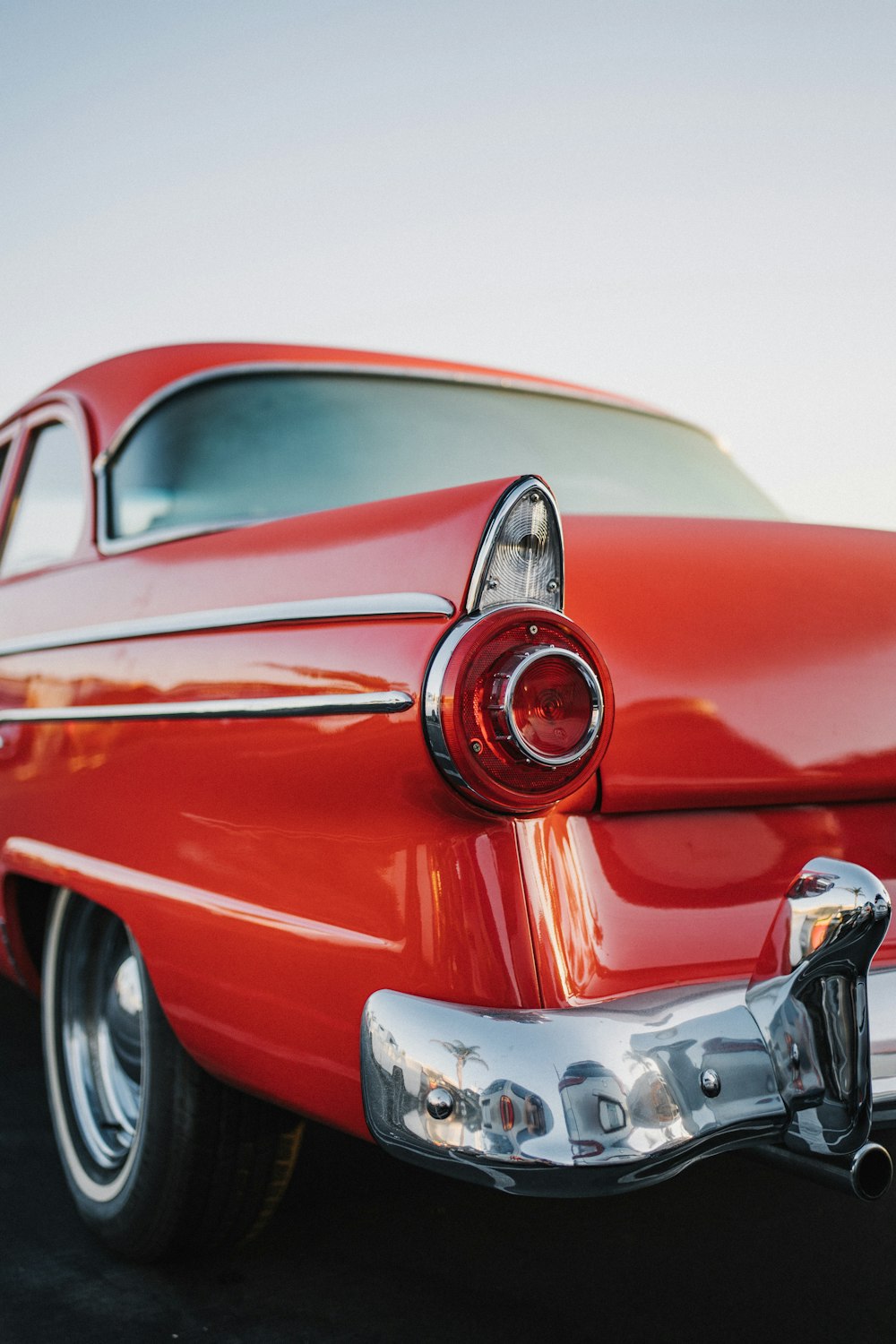 an old red car parked in a parking lot