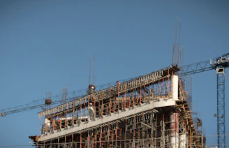 Modern construction site with cranes and steel framework under a clear sky.