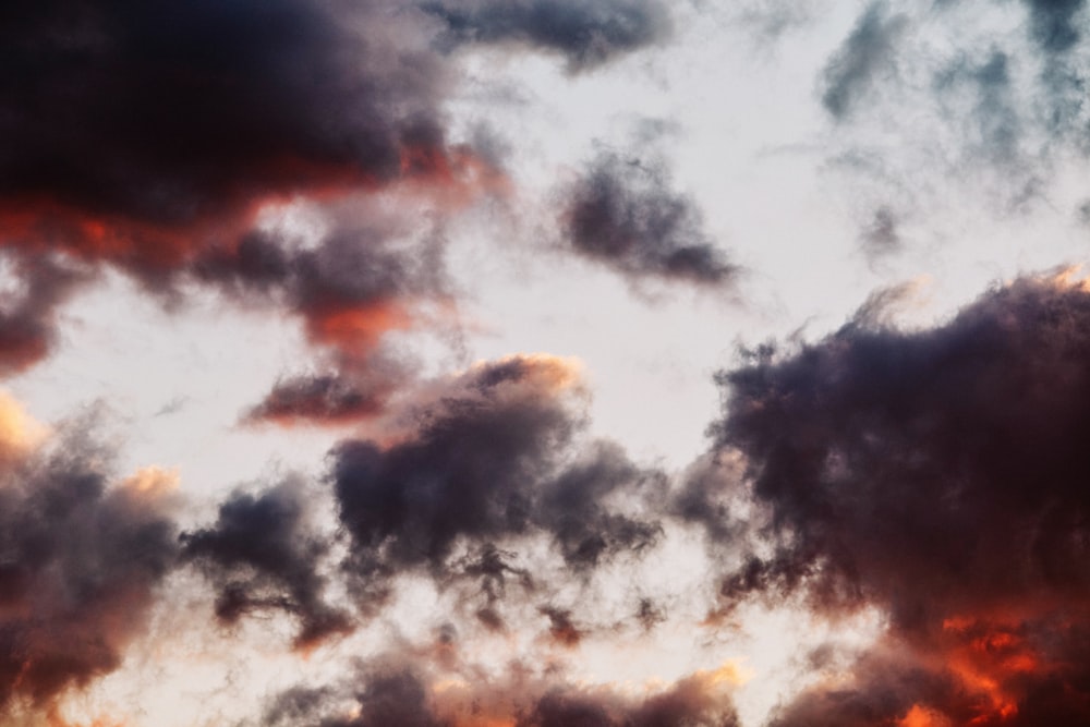 a plane flying through a cloudy sky at sunset