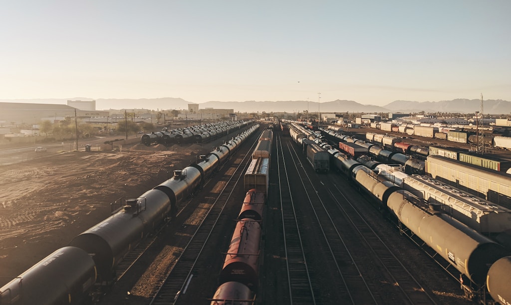 Looking at an aerial shot from a freeway onto a train yard during sunrise facing south.