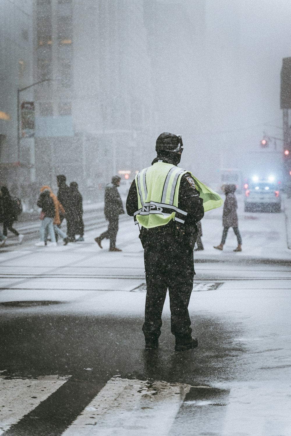 a police officer standing on the side of a road in the snow