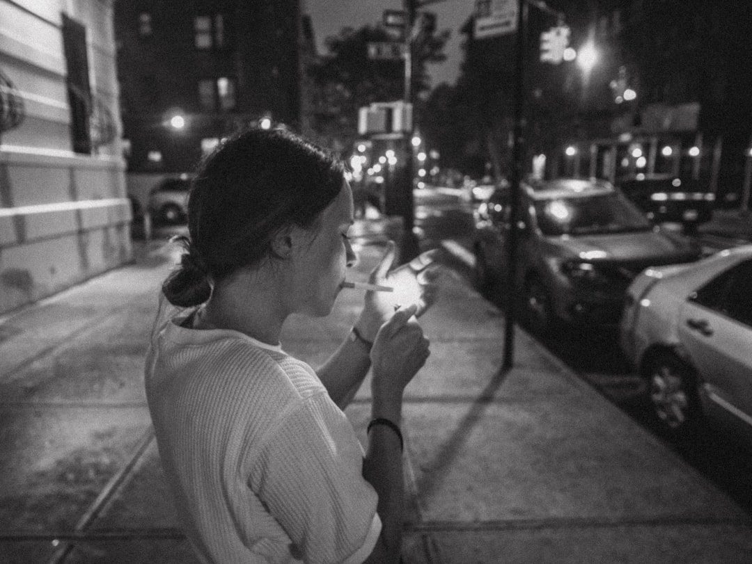 a woman smoking a cigarette on a city street, Smoking cigarettes in the city.