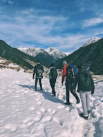 Snow-capped mountains with a small group hiking along a scenic trail.
