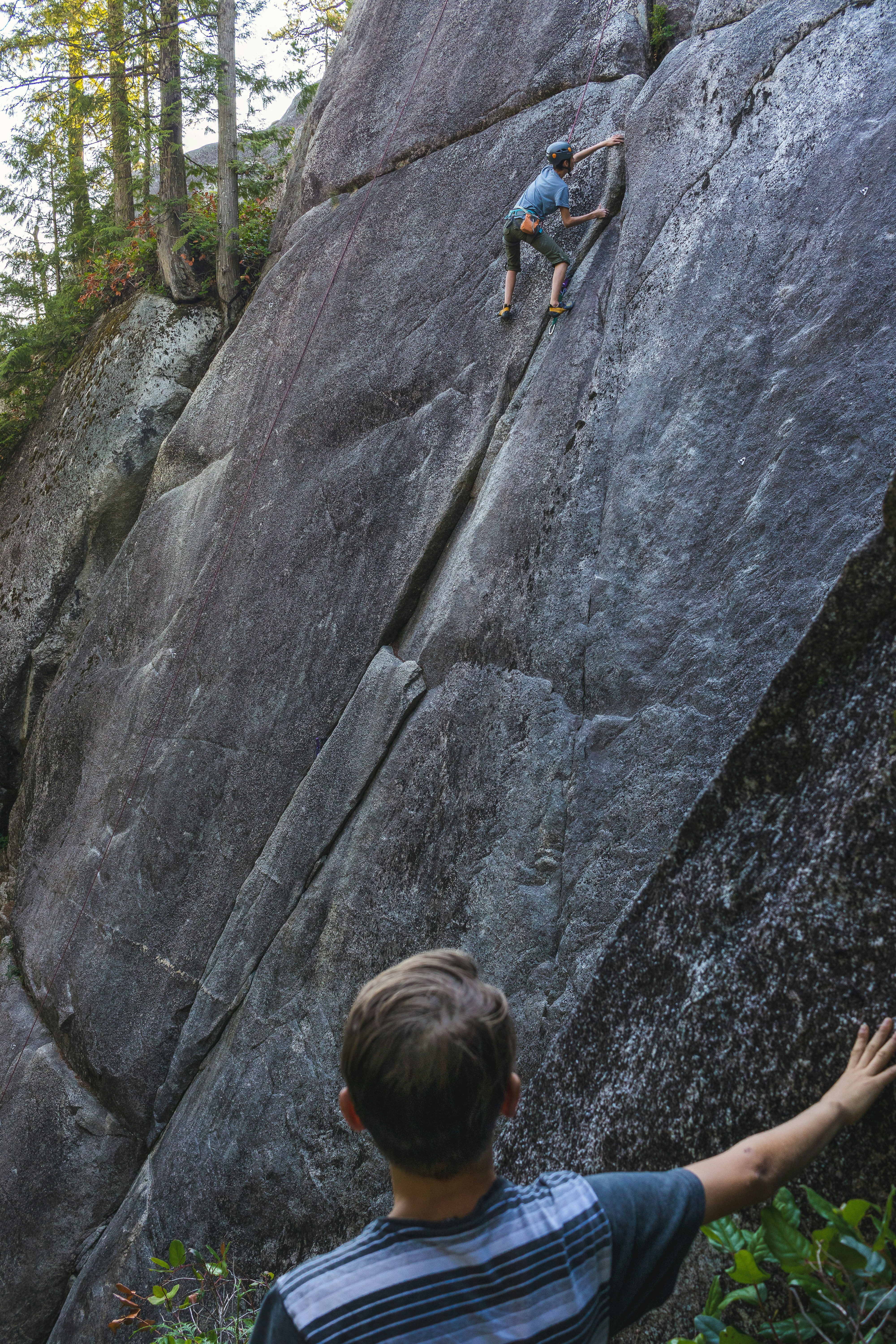 a man climbing up the side of a large rock