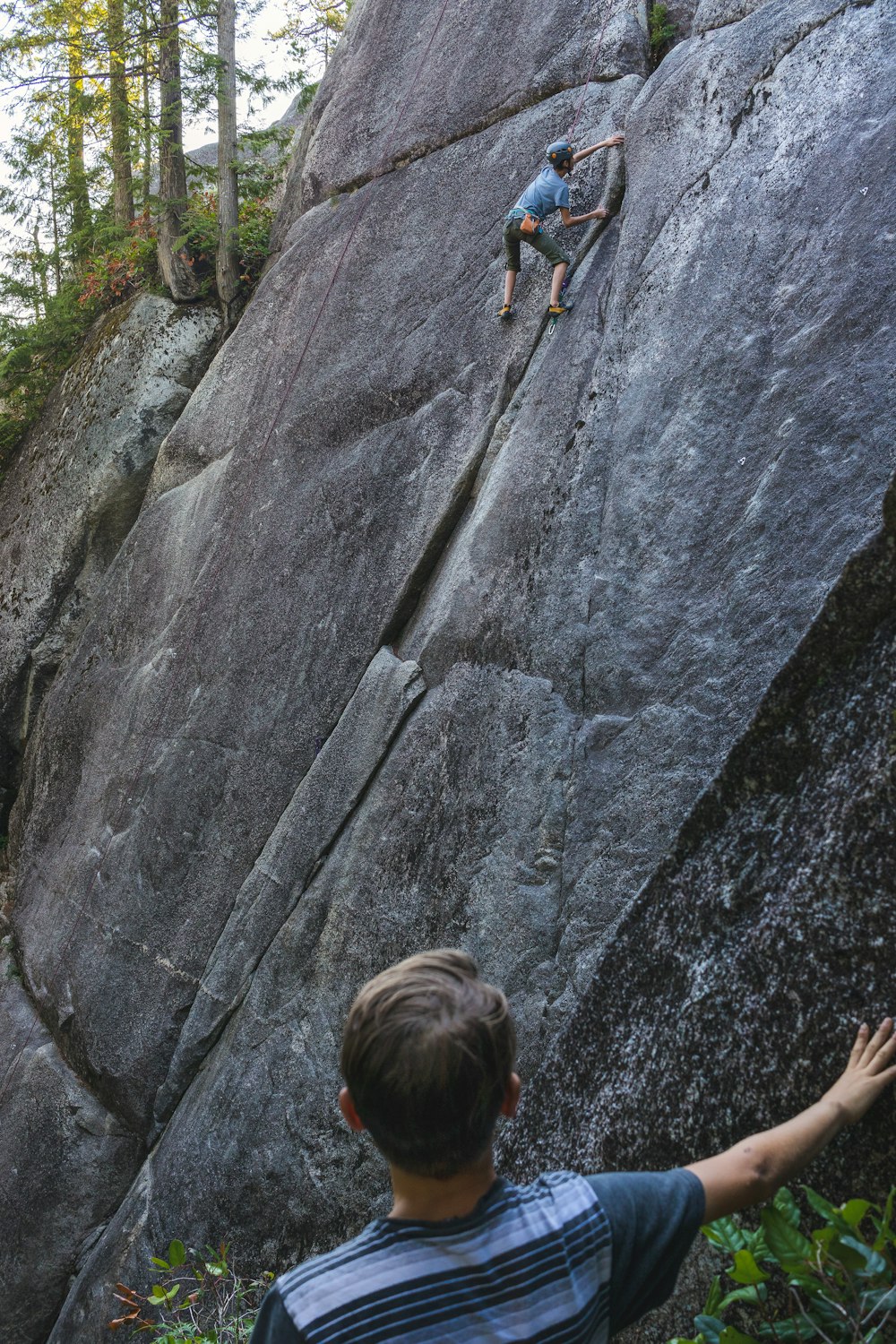 a man climbing up the side of a large rock