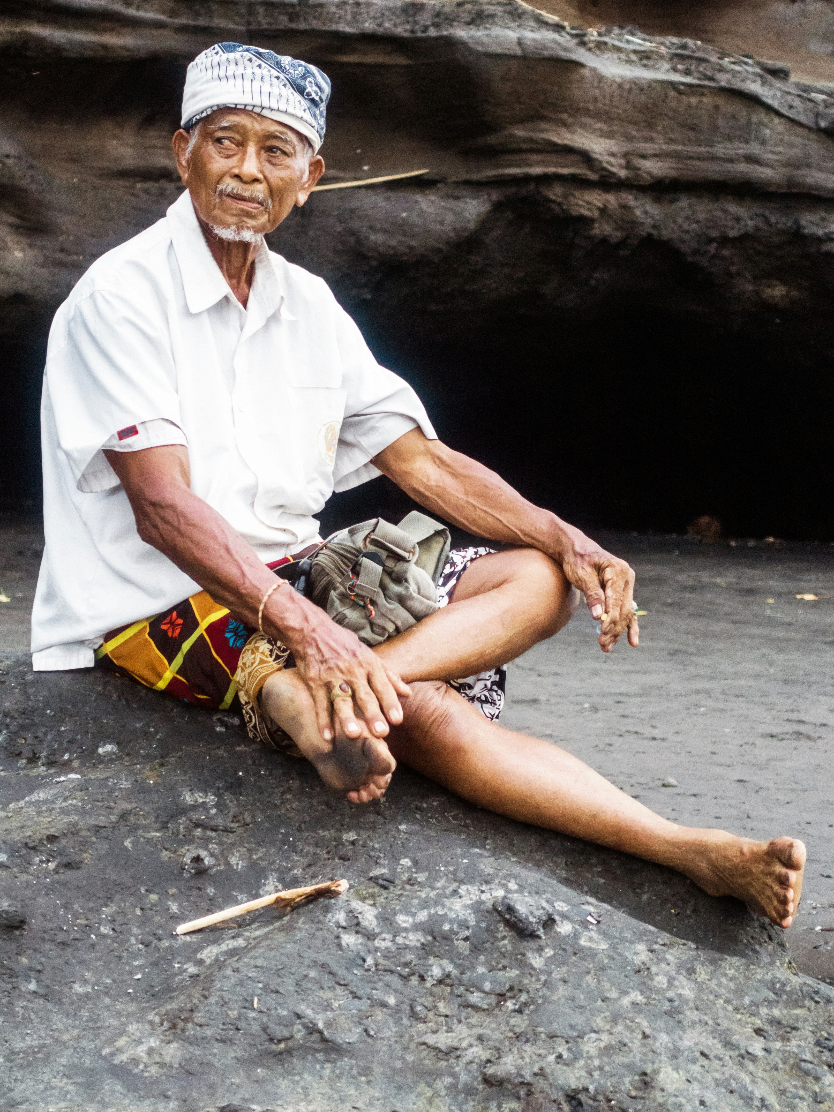 Seorang pria duduk di atas batu dengan kaki disilangkan