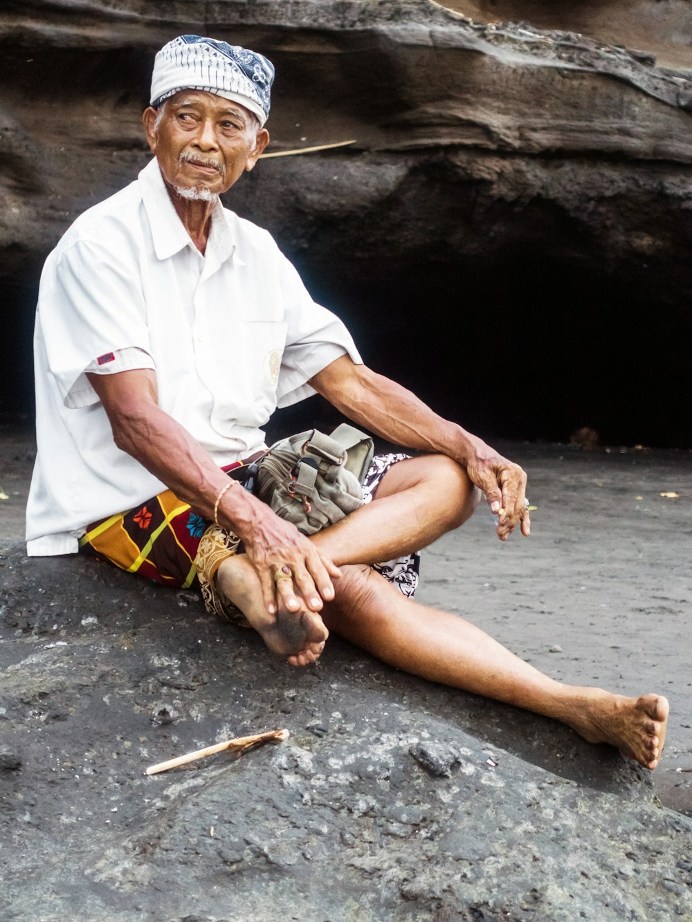 Un hombre sentado en una roca con las piernas cruzadas