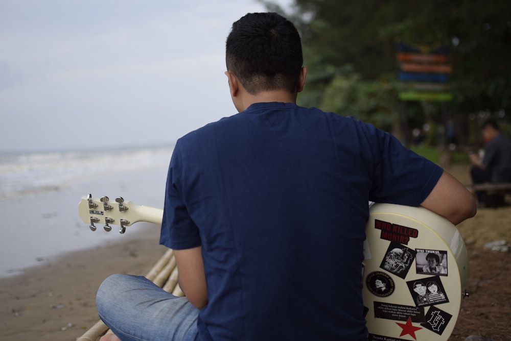 a man sitting on a bench holding a guitar