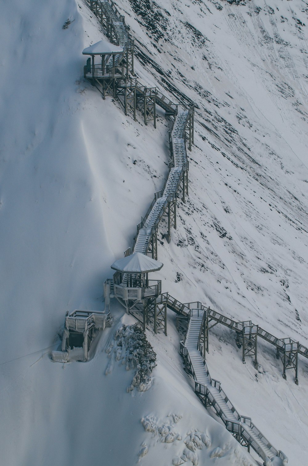 uma colina coberta de neve com uma estrutura de madeira em cima dela