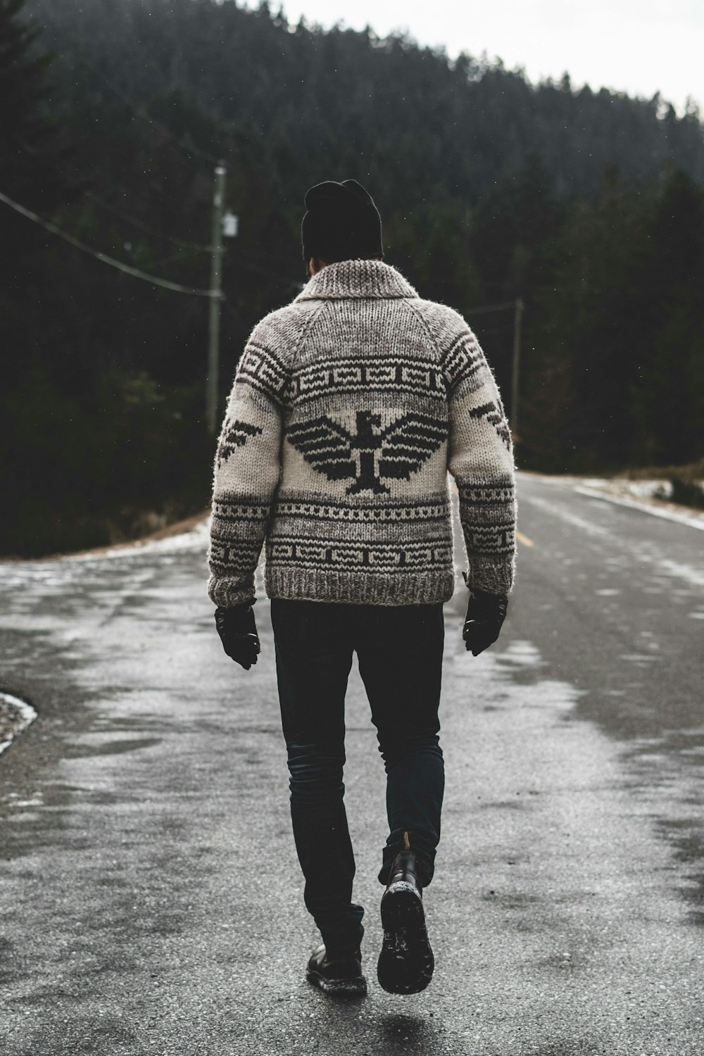 man in gray and black sweater standing on road during daytime