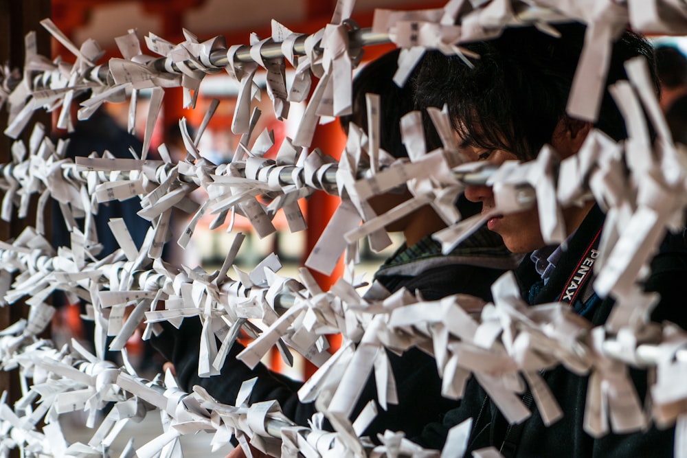 a man standing next to a wall covered in white paper