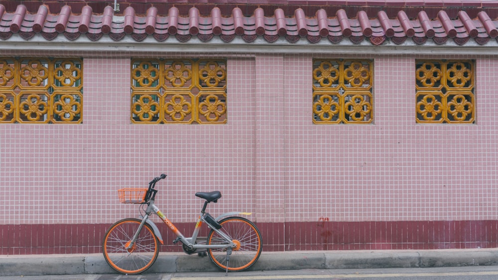 black bicycle parked beside red and white concrete wall