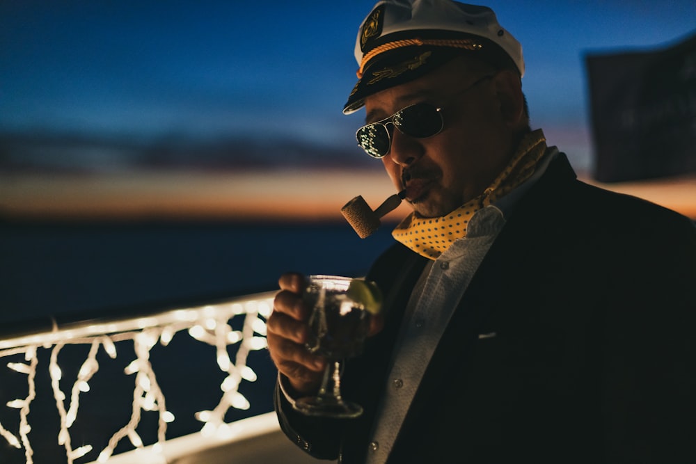a man smoking a cigar and drinking a glass of wine