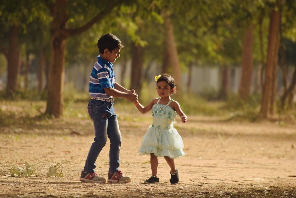 man and woman holding hands while walking on brown dirt road during daytime