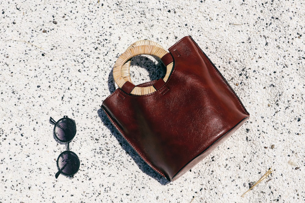brown leather pouch beside black sunglasses