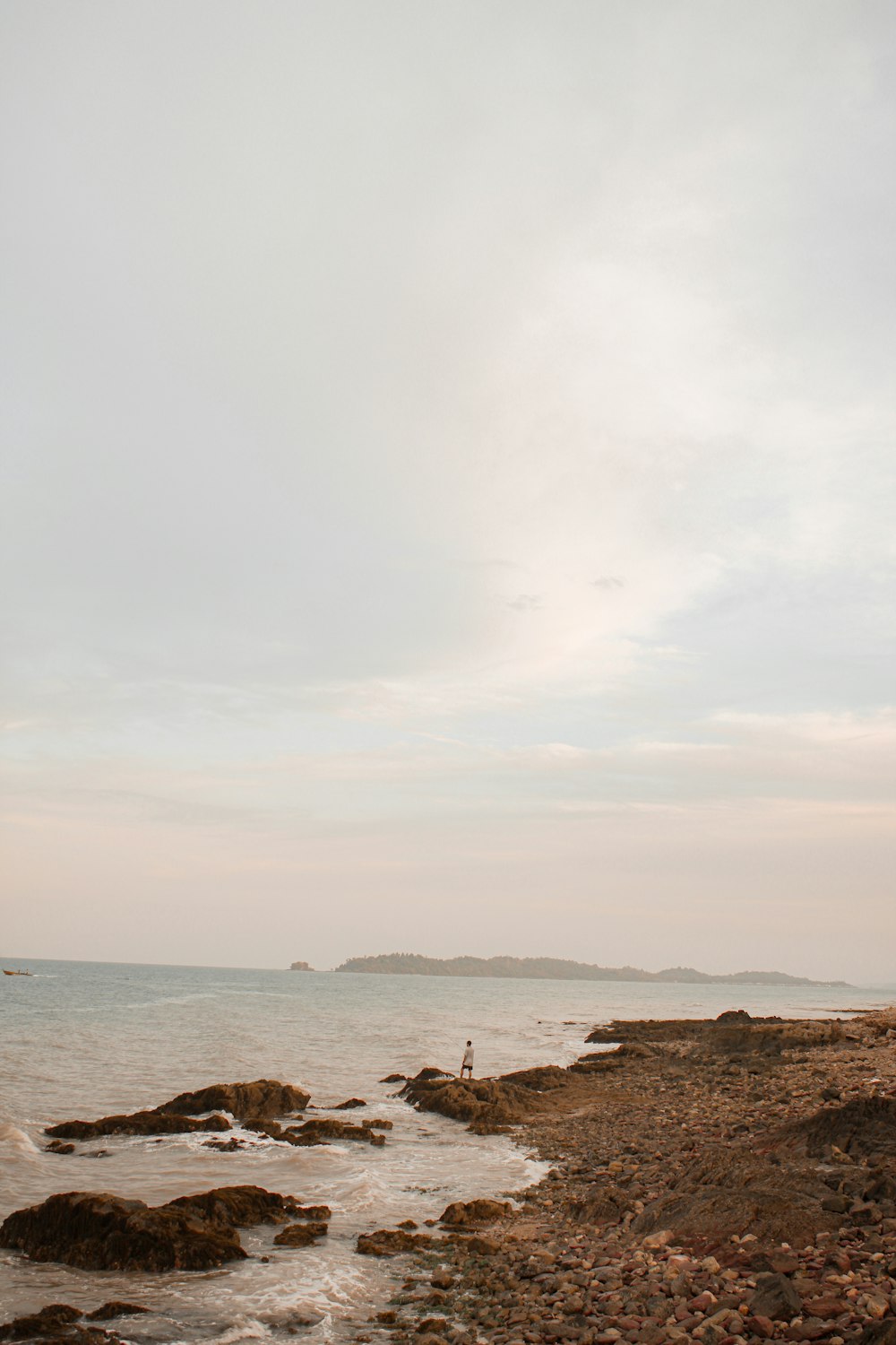 brown rocks on seashore under white clouds during daytime