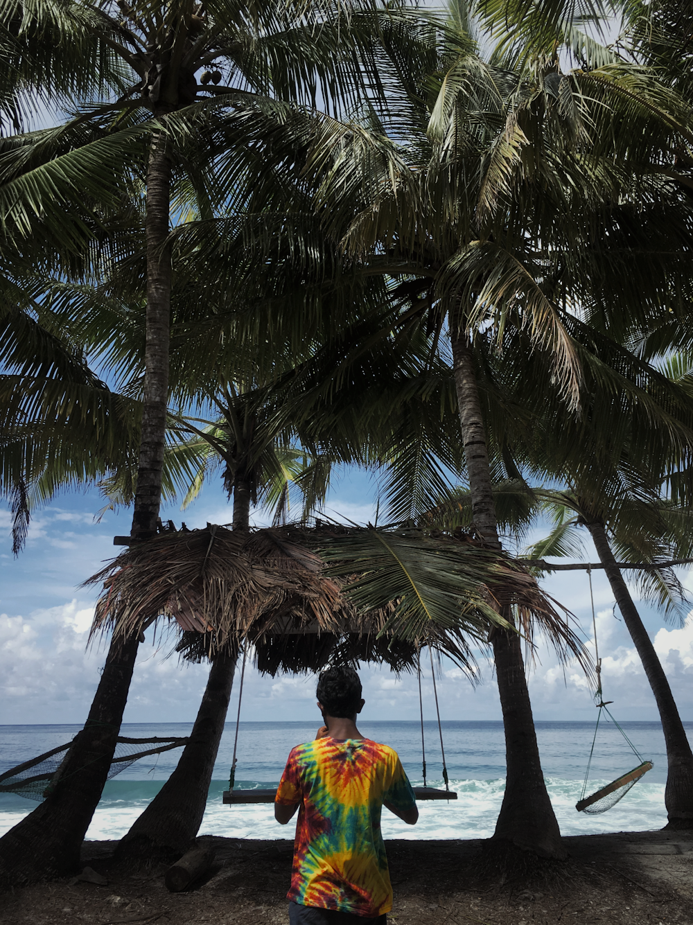 person in orange and yellow shirt standing near palm tree during daytime