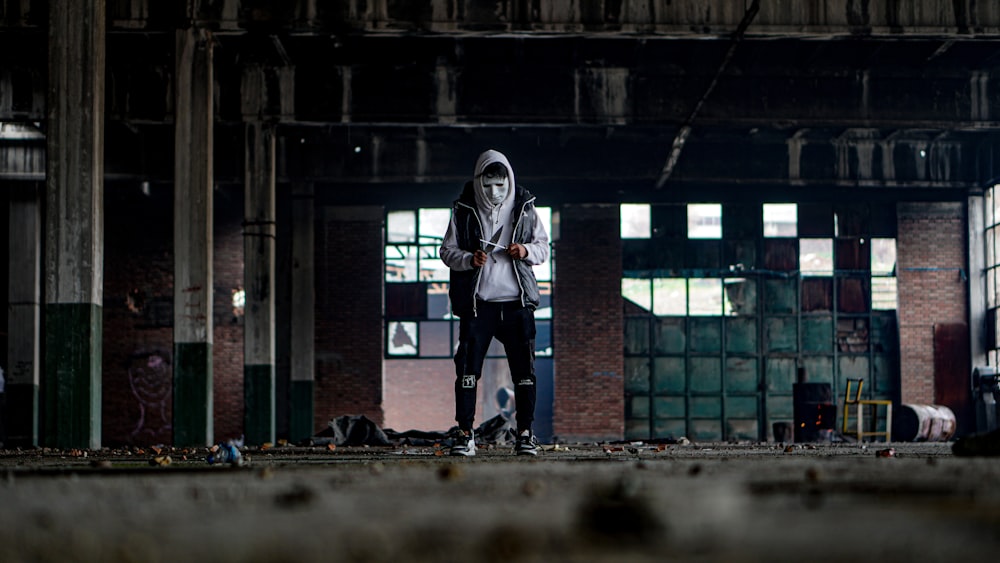 man in black and white jacket and black pants standing on gray concrete floor