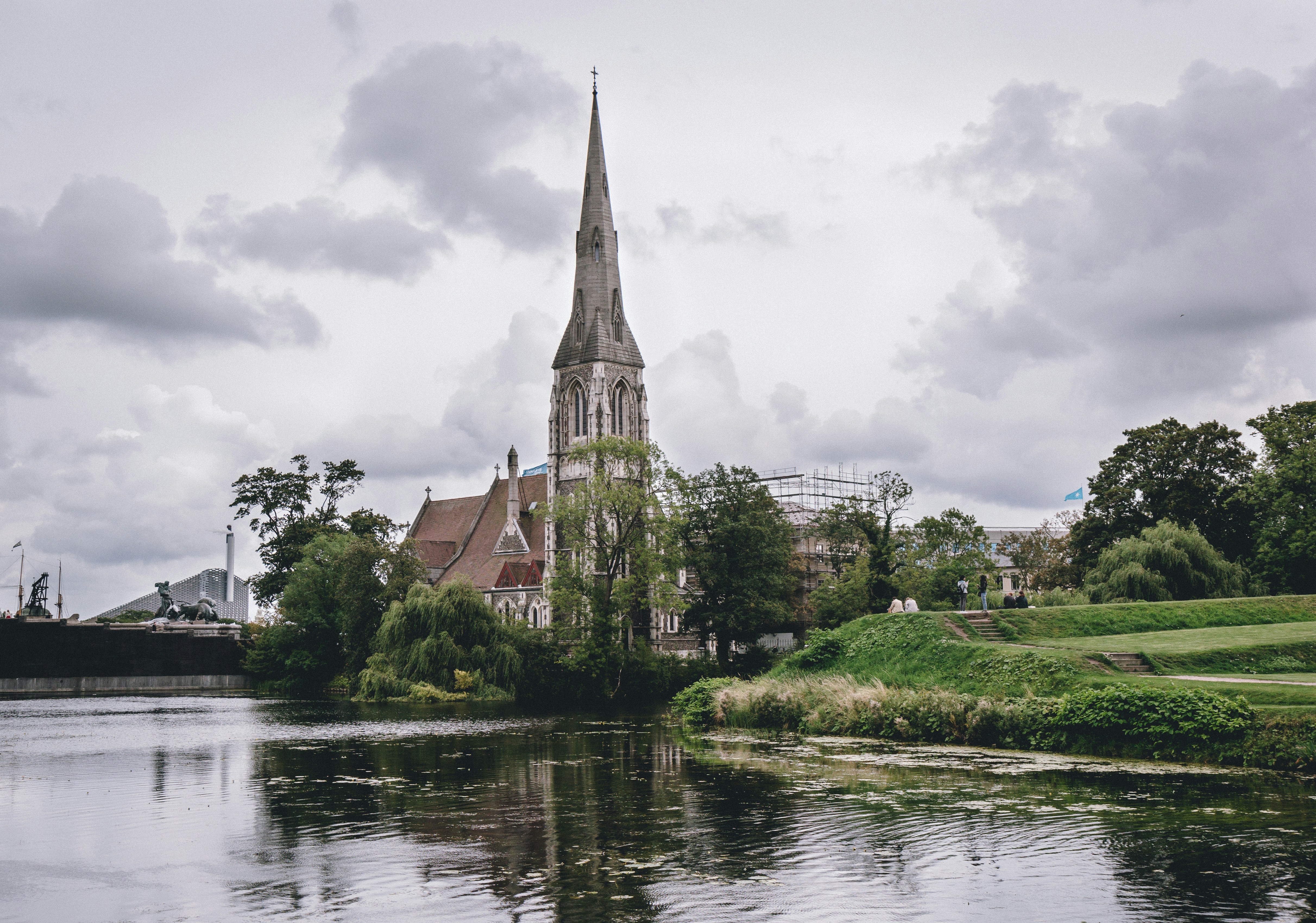 brown and gray concrete building near body of water under cloudy sky during daytime neoclassical teams background