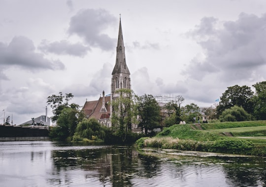 brown and gray concrete building near body of water under cloudy sky during daytime in St Alban's Church Denmark